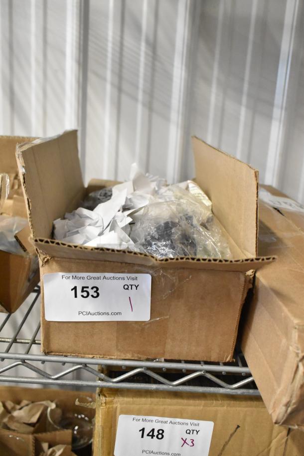 Cardboard box containing packed items, labeled "153 QTY 1, PCIAuctions.com," on metal shelf. Condition: Unspecified.