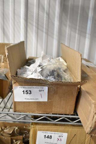 Cardboard box containing packed items, labeled "153 QTY 1, PCIAuctions.com," on metal shelf. Condition: Unspecified.