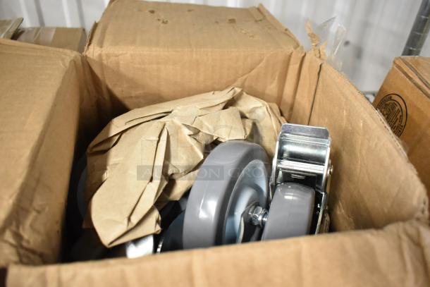 Box containing new gray caster wheels, partially wrapped in brown paper, featuring sturdy metal brackets.