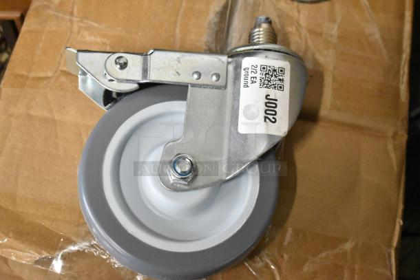 Industrial caster wheel with metal bracket, gray rubber tire, and brake. Label reads "2/2 EA ground J002." Condition: new.