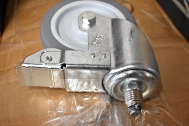 Industrial swivel caster wheel, metal bracket, gray rubber wheel, threaded stem, slight wear. Markings indicate manufacturing details.
