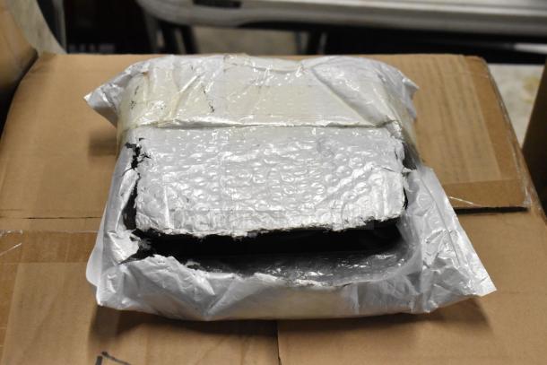 Damaged package wrapped in bubble wrap and tape, showing tears and wear, resting on a cardboard box, no visible markings.