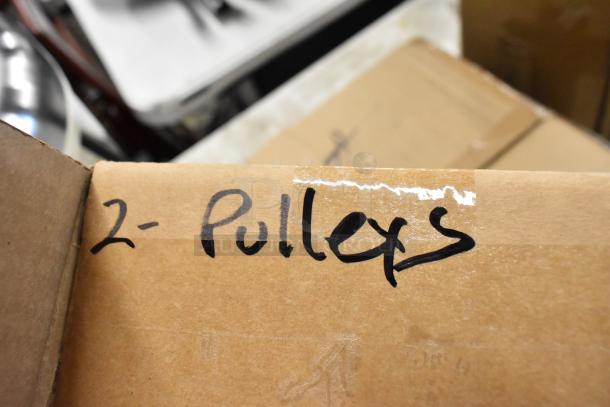Cardboard box labeled "2-Pulleys," indicating contents. Brown tape seals the label. Condition appears intact.