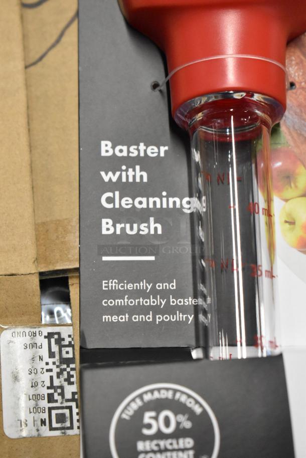 Red baster with clear measurement markings, includes a cleaning brush. Made from 50% recycled content. Efficient for meat and poultry.