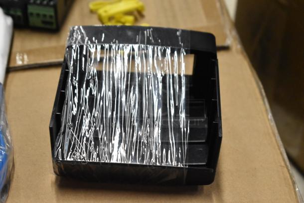 Black plastic housing, wrapped in protective film, on cardboard surface. Item appears new. No visible labels or markings.