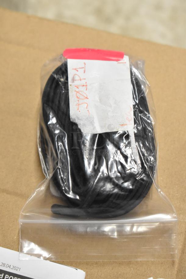 Coiled black cable in a sealed plastic bag with a handwritten label marked "30/4/21." Appears new, stored securely.