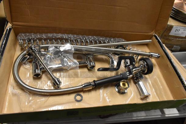 Chrome kitchen faucet set, new in box, includes sprayer, coiled hose, mounting hardware, and fittings.