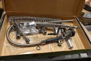 Chrome kitchen faucet set, new in box, includes sprayer, coiled hose, mounting hardware, and fittings.