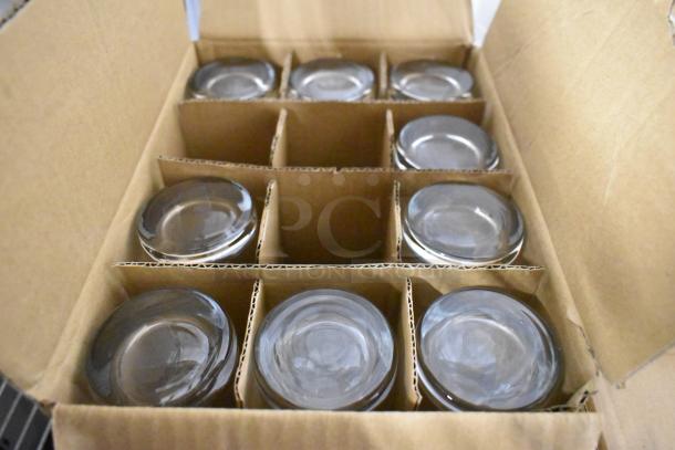 Box of 12 glass bowls, new condition, securely packed in cardboard dividers for protection, ideal for kitchen use or display.