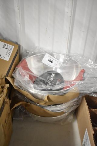 Stack of new Stir Fry Pans, aluminum, in plastic wrap and cardboard. Auction tag 166, quantity six.