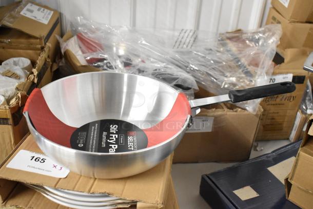 Emperor's Select aluminum stir fry pan, new, with black handle and red accent, placed on a cardboard box.