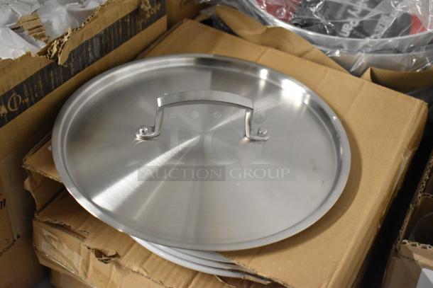Stainless steel pot lid with handle, resting on cardboard boxes, in new condition. No visible labels or markings.