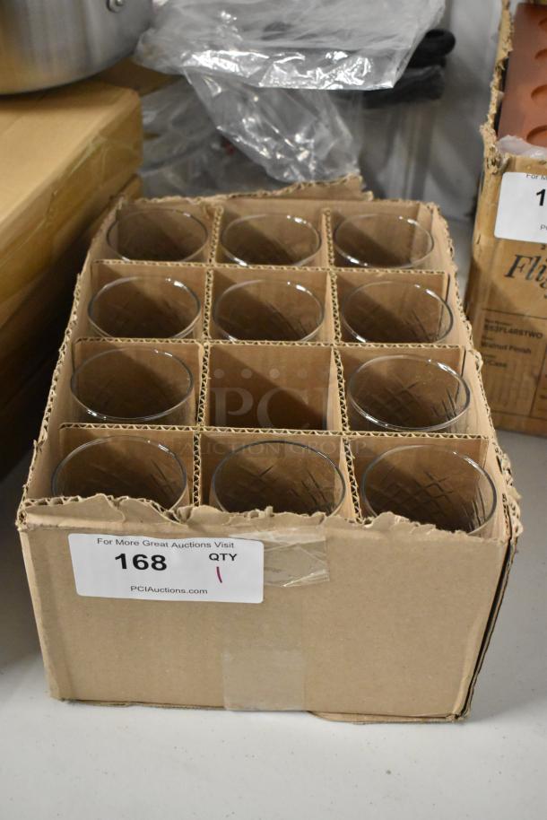 Box of 12 clear glass tumblers, new condition, in cardboard packaging. Label shows auction lot number 168, PCI Auctions.