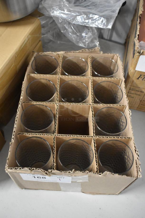 Box of 11 clear glass tumblers with textured surface, nestled in cardboard dividers. Auction label "168" visible on box.