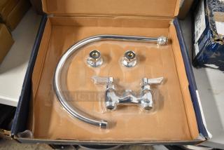 Chrome-plated faucet set in box. Includes spout and handles, new condition, packaging intact. Suitable for kitchen or bath.