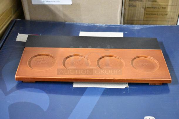Wooden tasting flight board with four circular indentations, in good condition, on display for auction.