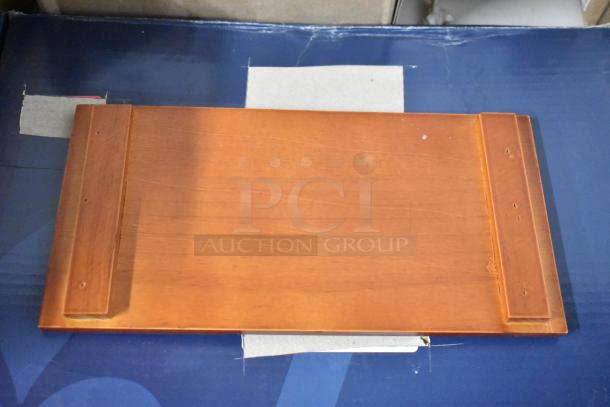 Wooden shelf or panel with mounting brackets, light brown finish, smooth surface, minor scratches, no visible labels.