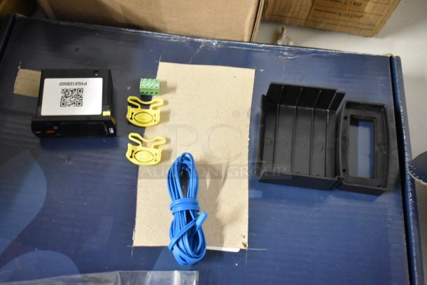 Electronics kit with a device labeled PX1Z0962, blue wire, yellow clips, connector, and black casing. Ideal for setup.