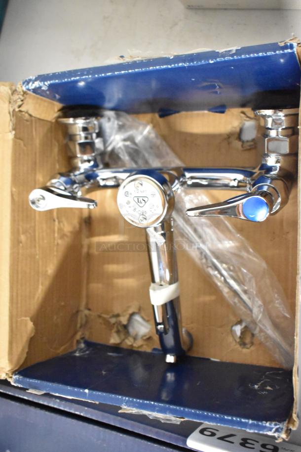 Chrome kitchen faucet in original packaging, dual lever handles, new condition, visible label indicates fittings size and model number.