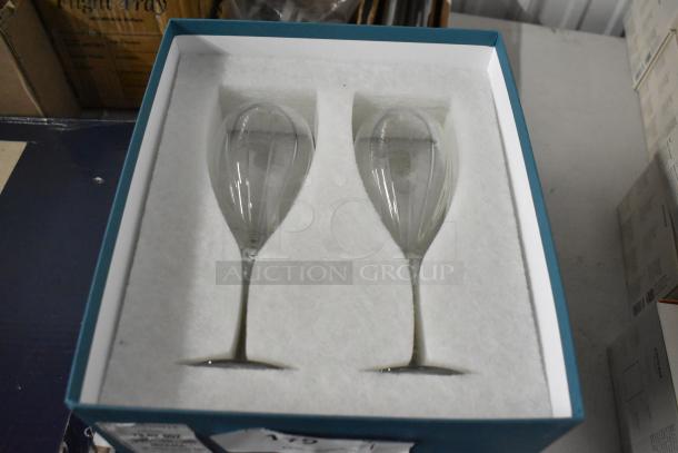 Two clear crystal champagne flutes in a blue box with protective padding, showcasing elegant, elongated design.
