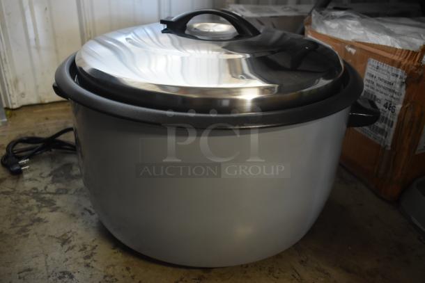Large electric rice cooker with a shiny stainless steel lid, side handles, and attached power cord. Appears in good condition.