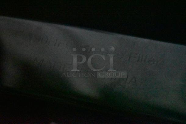 Blurred metal surface with faint markings stating "Made in China," indicating item's manufacturing origin.