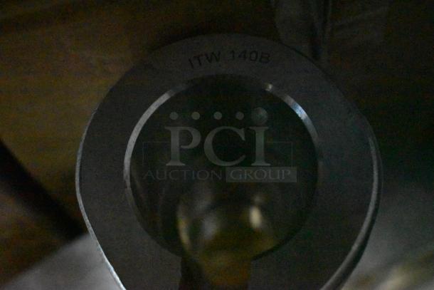 Close-up of a metallic cylinder with "ITW 140B" marking, indicating model or part number. Appears in good condition.