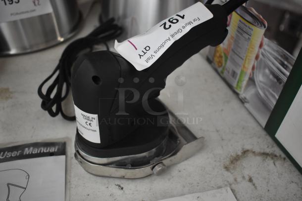 Electric fabric cutter with black handle, labeled "Made in China" and model number. Includes user manual. Item tag 192 visible.