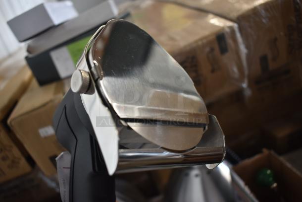 Stainless steel kitchen slicer with polish finish, reflective blade, and black handle, in excellent condition, near packaging boxes.