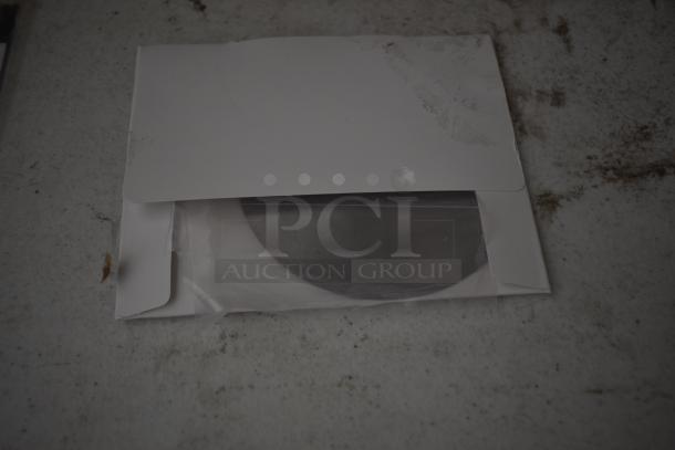Envelope with a disk partially visible inside, resting on a dirty surface. Disk appears new with no visible markings.