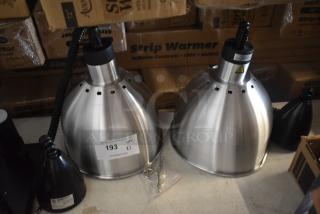 Two stainless steel heat lamps with coiled cords, shown on a table with cardboard boxes. Auction tag reads "193."