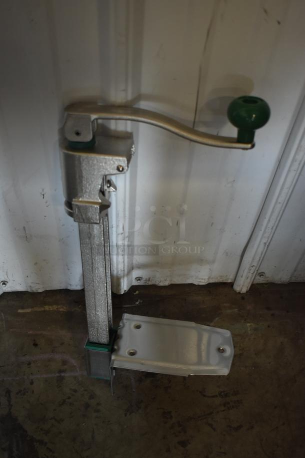 Manual truck landing gear with a green handle, steel construction, moderate wear, mounted on a metal base.