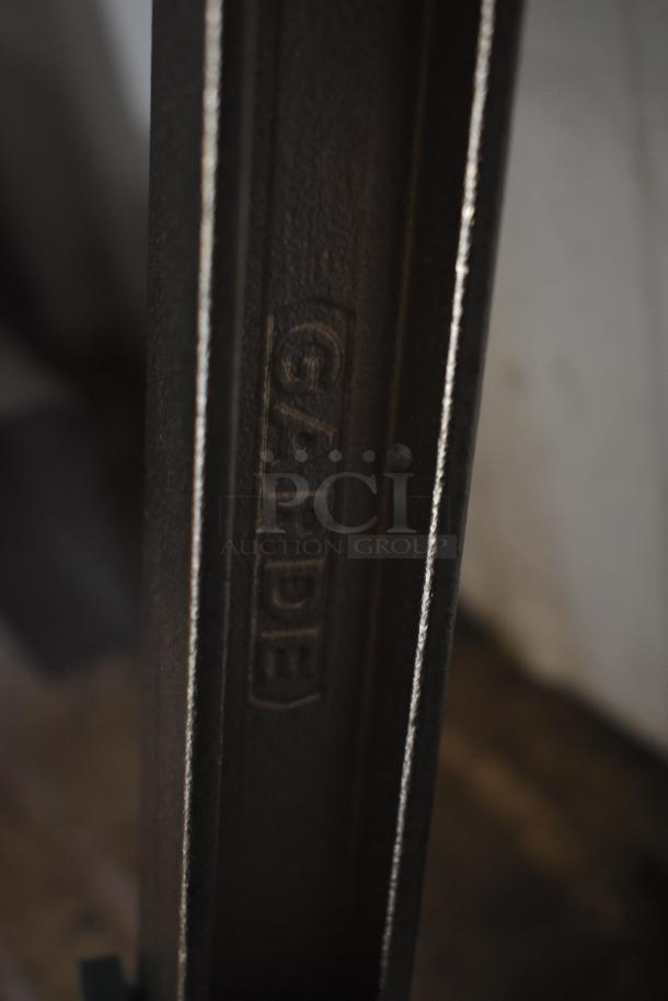 Close-up of a black metal structure with the word "GARDE" embossed, showing slight wear.