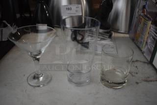 Set of three drinking glasses: martini glass, tall tumbler, and whiskey glass, in good condition on a countertop.