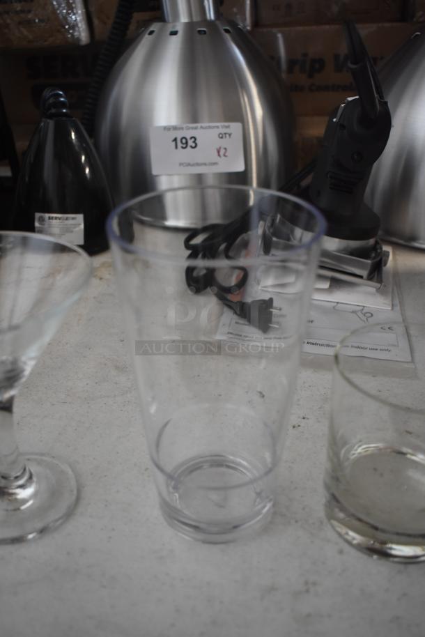Stainless steel electric kettle with label "193" and "QTY 2" visible, surrounded by glassware.