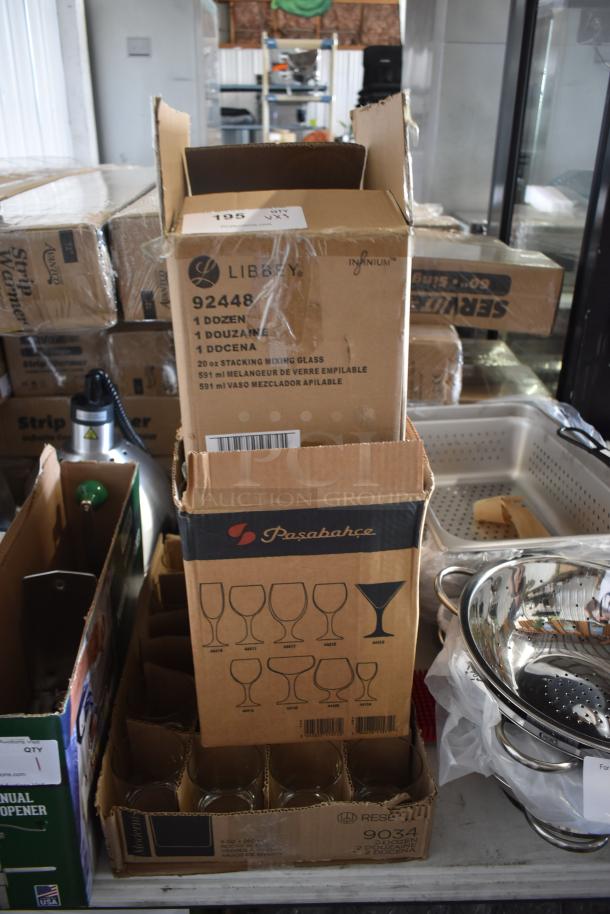 Boxes of glassware by Libbey and Pasabahce, containing stacking mixing glasses and stemware, in sealed packaging.
