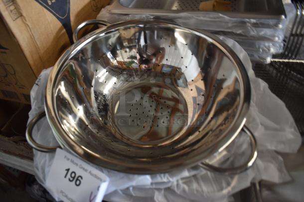Stainless steel colander with dual handles, reflective surface, and perforations, in excellent condition. Auction tag number 196.