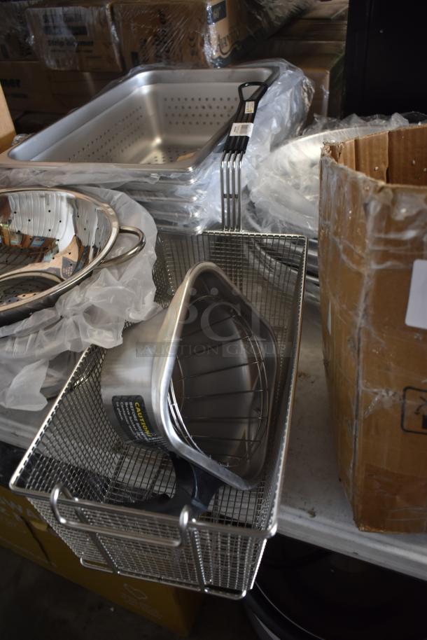 Stacked stainless steel colanders and roasting pans, new condition, with white plastic packaging and caution labels visible.