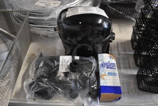 Black compressor unit with visible label, accompanied by a Catch-All filter-drier box and wrapped accessories, new condition.