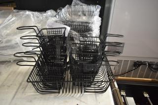 Stack of black metal fry baskets with handles on a countertop, wrapped in plastic, in excellent condition.