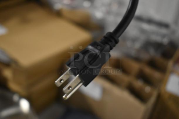 Close-up of a black two-prong power plug with cord, in new condition, against a blurred background.