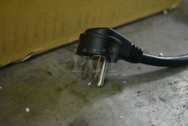 Black three-prong electrical plug with intact prongs, shown on a concrete surface.
