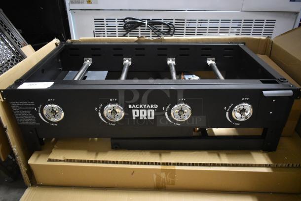 Backyard Pro gas burner range, four adjustable dials, black metal, new in box, lighting instructions visible on side.