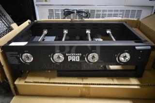 Backyard Pro gas burner range, four adjustable dials, black metal, new in box, lighting instructions visible on side.