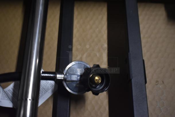 Gas regulator with black hose attached, metallic body with visible connector. Appears new with visible label text.