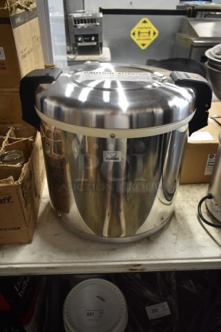 Zojirushi rice warmer, stainless steel, with caution label on top, features carrying handles. In good condition.