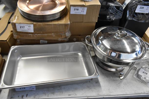 Stainless steel chafing dish set with lid and stack of copper plates. Condition: new. Auction tags visible with item numbers 216, 217, 218, 219.