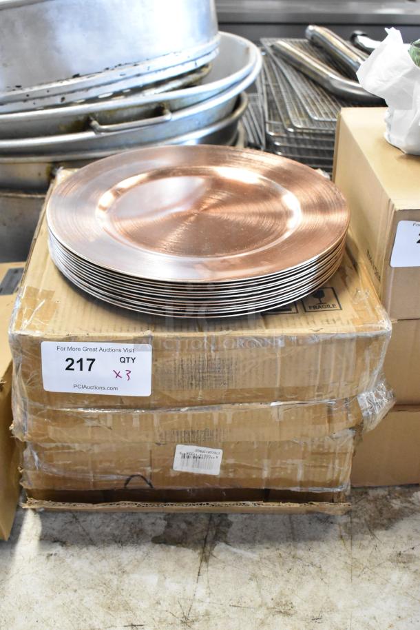 Stack of copper-colored plates on a cardboard box labeled "217," indicating an auction lot of three. Plates appear in good condition.