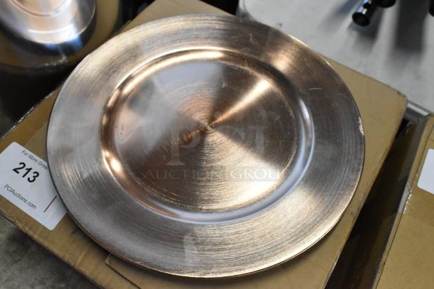 Metallic charger plate with brushed finish, slight edge wear, placed on cardboard box. Auction tag reads "213".