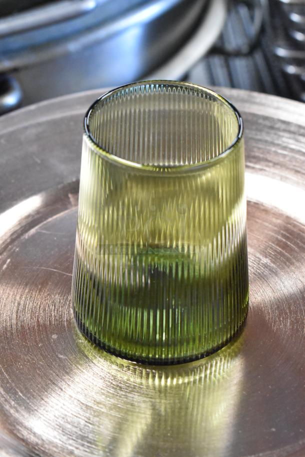 Green ribbed glass tumbler, cylindrical, excellent condition, reflective metallic surface base. 